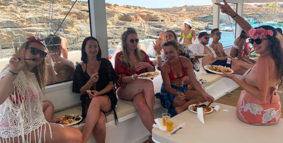 Malta: Blue Lagoon Evening Catamaran Cruise - Onboard life: sun beds, bar service, ladders, and dancing